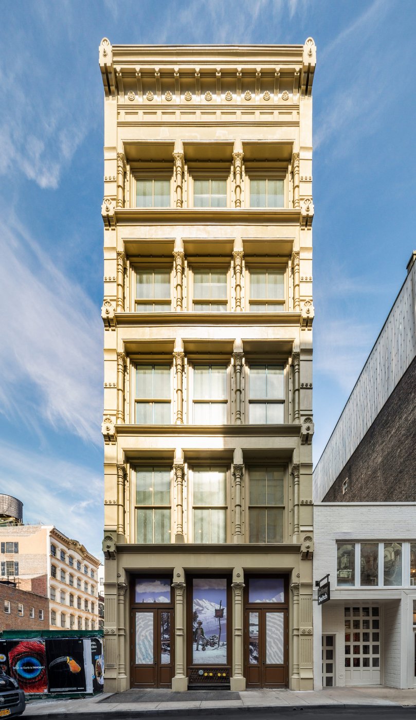 74 Grand Street, a six-story cast-iron SoHo facade with ornamented columns and arched windows, photographed intact in daylight.